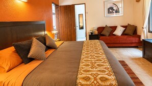 A hotel room with a large bed, a red sofa, a wooden door, and a framed picture on the wall. - Nightingale | King, fireplace and garden (Valle de Bravo)