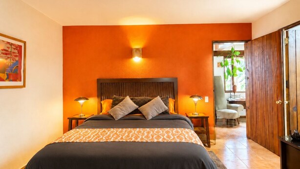 A bedroom with a large bed, two bedside lamps, and a wooden headboard. - Nightingale | King, fireplace and garden (Valle de Bravo)