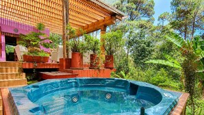 A hot tub in a garden setting with a wooden deck and potted plants. - Quetzal Suite | Terrace, fireplace and jacuzzi (Valle de Bravo)