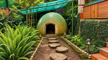 A garden pathway leading to a green dome structure, surrounded by lush greenery and stone steps.