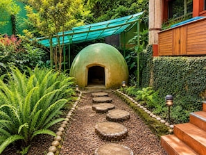 A garden pathway leading to a green dome structure, surrounded by lush greenery and stone steps.