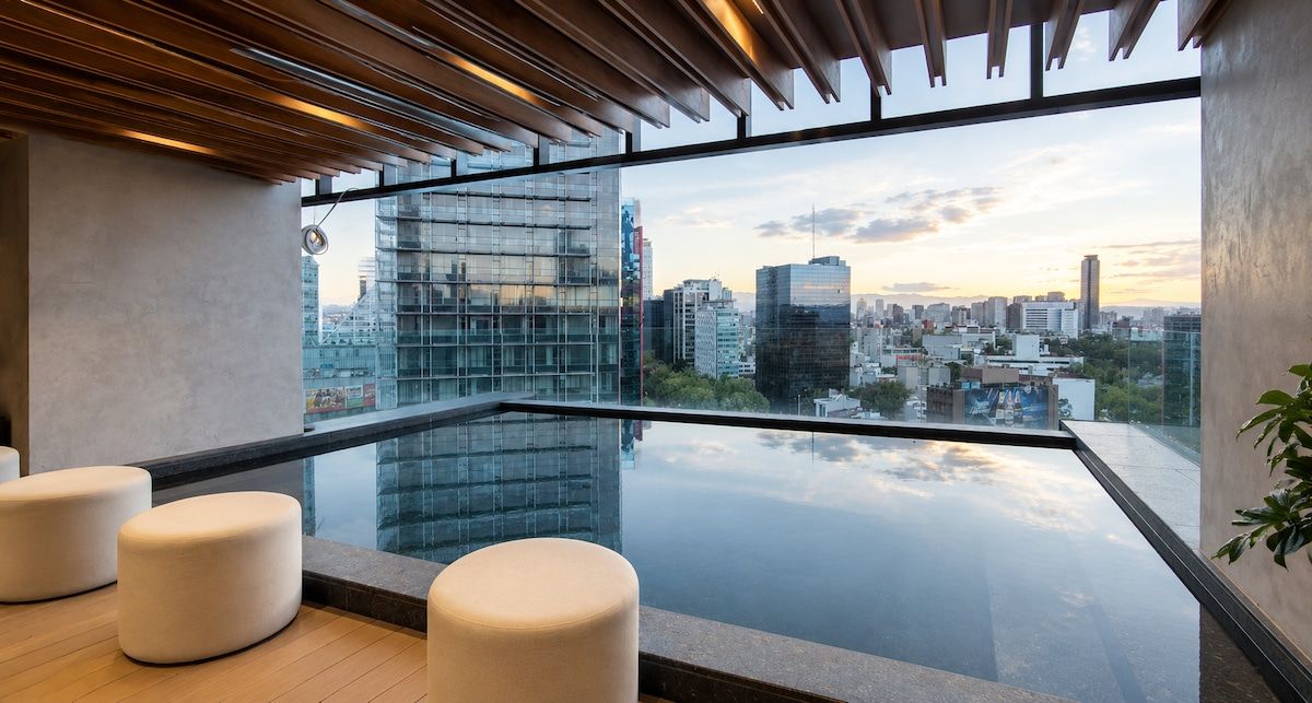 Une terrasse moderne sur le toit, dotée d’une barrière en verre, offrant une vue sur les toits de la ville et aménagée avec un mobilier minimaliste.