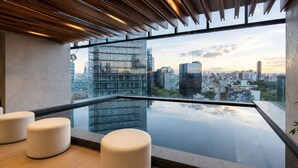 A modern rooftop terrace with a glass barrier, city skyline view, and minimalist seating. - Premium Loft Reforma | View + Pool + Gym (Mexico City)
