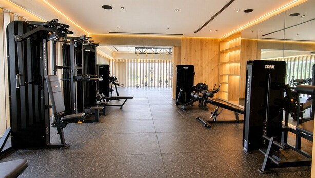 A gym with various exercise machines, a wooden wall, and a large window. - Premium Loft Reforma | View + Pool + Gym (Mexico City)