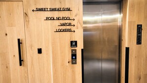 An elevator interior with wooden paneling and a sign indicating directions to the sweet sweat gym, pool, vapor, and lockers. - Premium Loft Reforma | View + Pool + Gym (Mexico City)