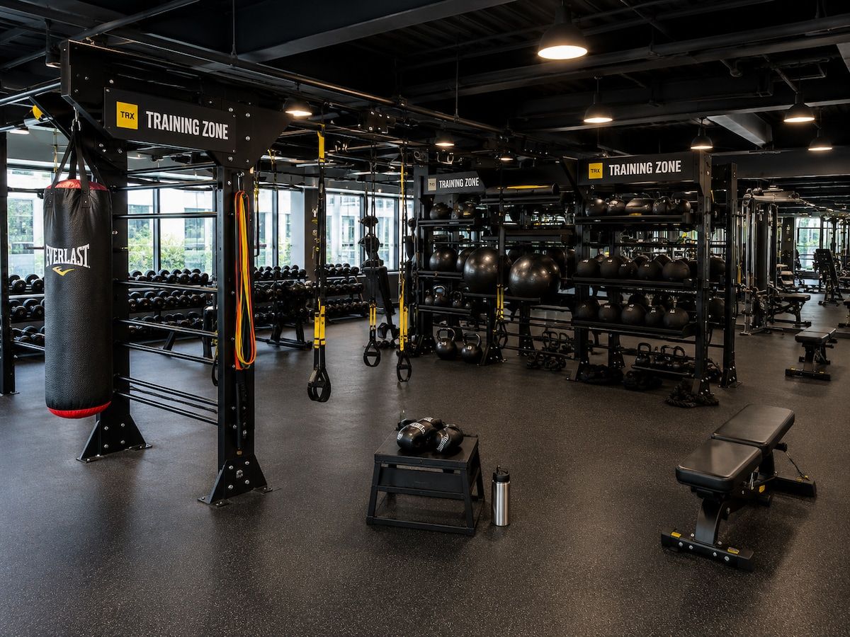 Ein Fitnessstudio mit verschiedenen Trainingsgeräten, darunter Kurzhanteln, Kettlebells und ein Sandsack.