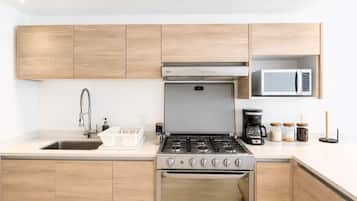 A modern kitchen with wooden cabinets, a stainless steel stove, a microwave, and a coffee maker.