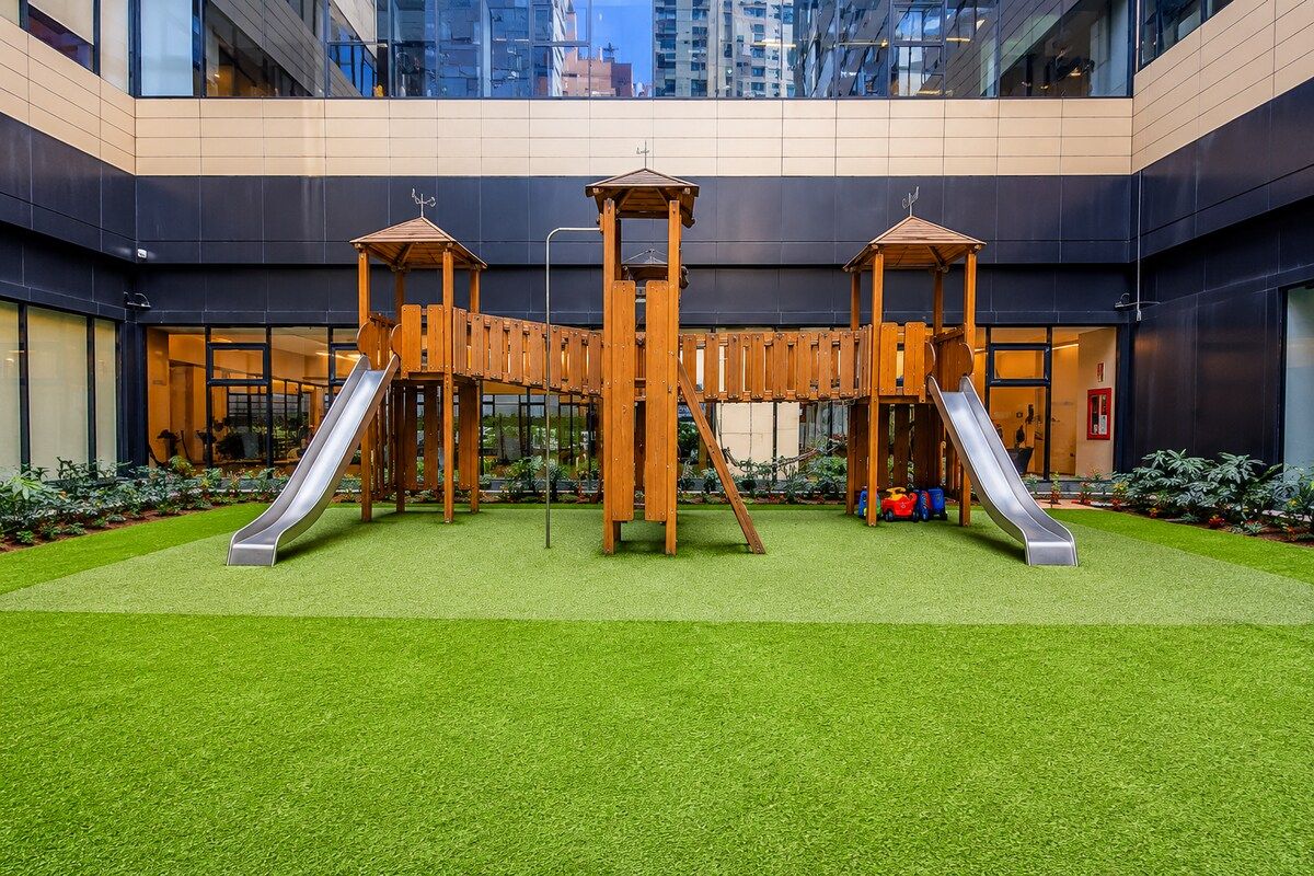 A playground with two slides and a climbing structure in an urban setting.