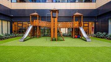 A playground with two slides and a climbing structure in an urban setting.