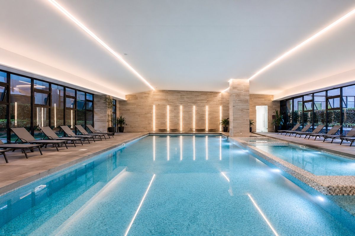 Una piscina interior con sillones de descanso y una pared de piedra.