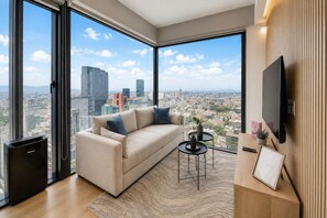 A modern living room with a large window, a sofa, a coffee table, and a flat-screen TV. - Luxury Condo w/ City Views, Pool, & Gym Access (Mexico City)