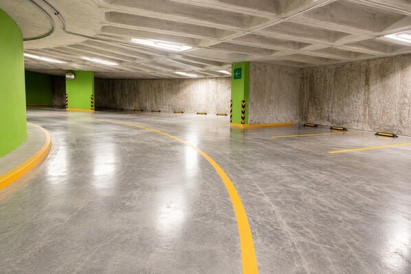 A multi-level underground parking garage with concrete walls, yellow parking lines, and green pillars. - Skyline Views in Reforma | Pool, Gym, Central (Mexico City)