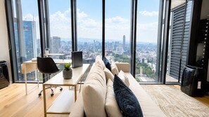 A modern living room with a sofa, a coffee table, and a view of a cityscape through large windows. - Skyline Views in Reforma | Pool, Gym, Central (Mexico City)