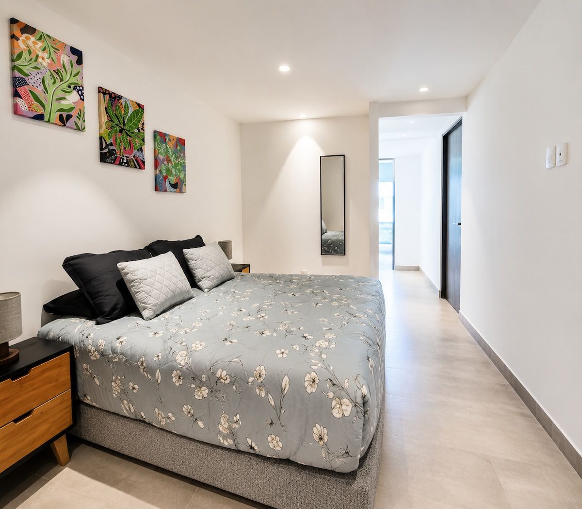 A modern bedroom with a large bed, bedside tables, and artwork on the wall.