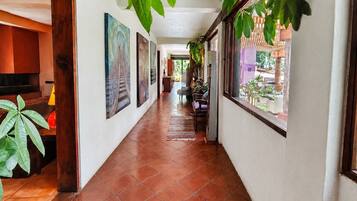 A hallway with tiled flooring, framed artwork on the walls, and a view of the outside through a window.