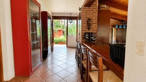 A kitchen with a brick wall, wooden cabinets, and a dining area with chairs. - Paloma Suite | Triple, breakfast and parking (Valle de Bravo)