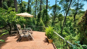 A patio with a table and chairs, surrounded by a wooden fence and lush greenery. - Paloma Suite | Triple, breakfast and parking (Valle de Bravo)