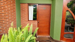 Una puerta de madera con el número 10, un muro de ladrillo y follaje verde.