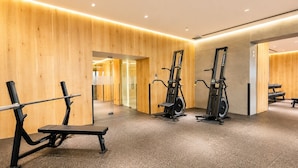 A gym with exercise equipment, wooden walls, and a mirrored wall. - 1BR Executive Reforma View + Pool + Cowork (Mexico City)