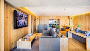 A modern interior with a grey sofa, wooden walls, a flat-screen TV, and a reception desk. - 1BR Executive Reforma View + Pool + Cowork (Mexico City)