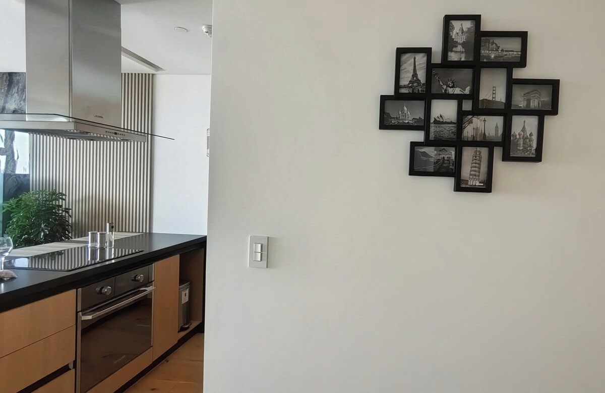Eine Küche mit modernem Design, ausgestattet mit einer Edelstahl-Dunstabzugshaube, einer schwarzen Arbeitsplatte und einem eingebauten Backofen.