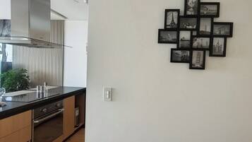 A kitchen with a modern design, featuring a stainless steel range hood, a black countertop, and a built-in oven.