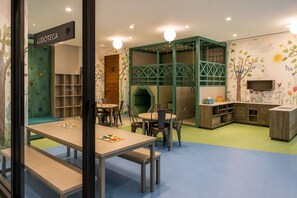 Een speelruimte voor kinderen met klimwanden, tafels en stoelen.