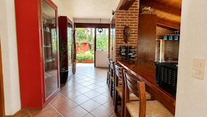 Cozinha com parede de tijolos, armários de madeira e piso de azulejos.