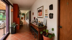 Corredor com porta de madeira marcada com o número 4, balcão de recepção com um banco e plantas em vasos.