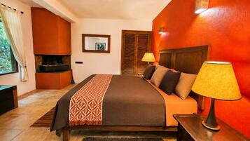 A hotel room with a bed, bedside lamps, a wooden headboard, a mirror, and a fireplace.