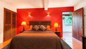 Camera da letto con un letto grande, due lampade ai comodini, una testiera in legno e una parete rossa.