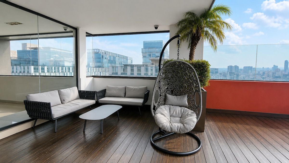 A modern balcony with a sofa, a hanging chair, and a small table.