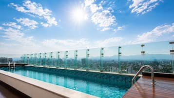 A rooftop pool with a glass railing, offering a cityscape view.
