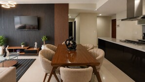 Una cocina moderna con estufa integrada, un televisor de pantalla plana en la pared y un comedor con mesa y sillas de madera.