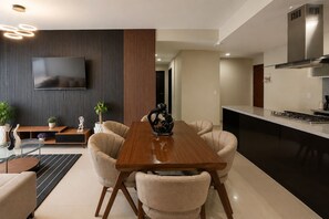Eine moderne Küche mit Einbauherd, einem flachbildfernseher an der Wand und einem Essbereich mit Holztisch und Stühlen.