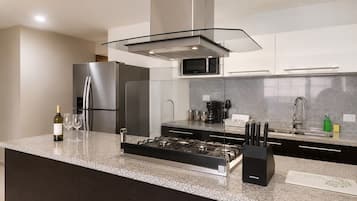 A modern kitchen with stainless steel appliances, a granite countertop, and a glass hood over the stove.