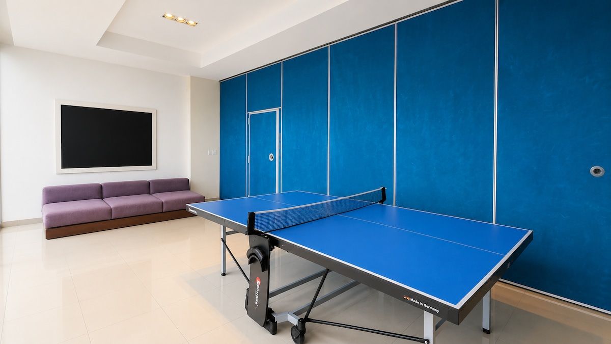 Et rum med et pingpongbord, en sofa og en stor blå væg.