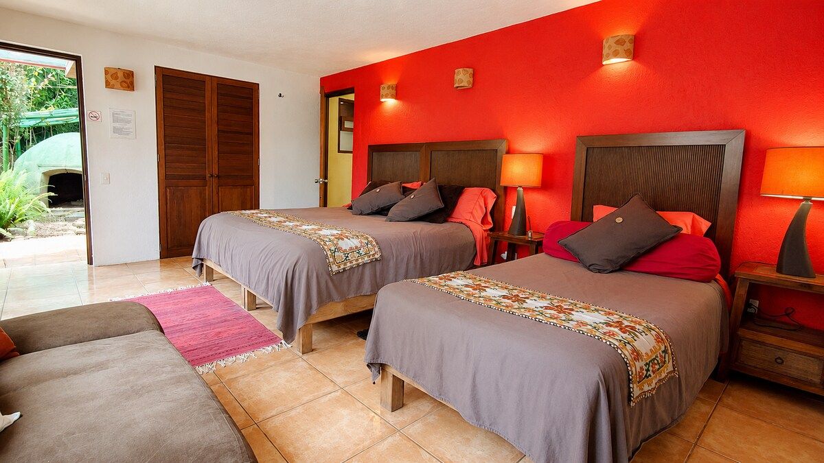 A hotel room with two beds, a sofa, and a small table.