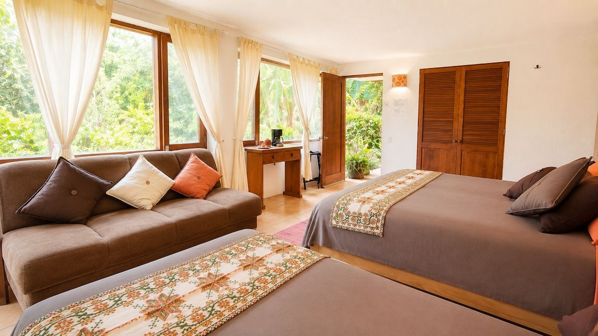 A bedroom with two beds, a desk, and a sofa.