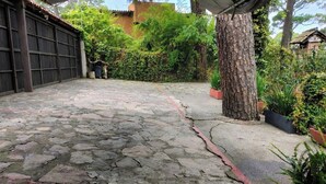 A paved courtyard with a wooden gate, surrounded by greenery and a tree trunk. - Sparrow | King and Breakfast in the Woods (Valle de Bravo)