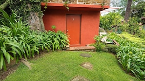 A red door with the number 9, surrounded by a well-maintained garden with various plants and a stone pathway leading to the door.