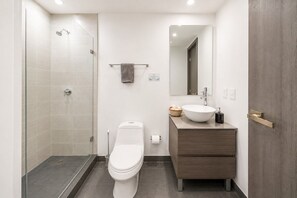 Ein modernes Badezimmer mit Duschkabine aus Glas, Toilette, Waschtisch und Spiegel.