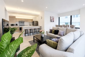 A modern living room with a sofa, coffee table, and a kitchen in the background. - Polanco Condo: Heated Pool, Jacuzzi, Near Antara (Mexico City)