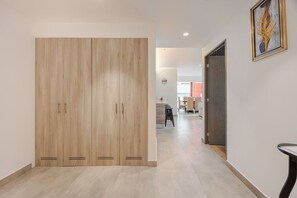 A hallway with a wooden wardrobe, a dining area, and a framed artwork on the wall. - Polanco Condo: Heated Pool, Jacuzzi, Near Antara (Mexico City)