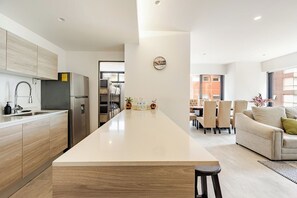 A modern kitchen with a central island, a dining area with a sofa and chairs, and a view of the outside. - Polanco Condo: Heated Pool, Jacuzzi, Near Antara (Mexico City)