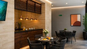 A modern dining area with a round table, black wicker chairs, and a wooden counter with pendant lighting. - Polanco 4BR Neuchatel | Pool, Jacuzzi, Gym, Antara (Mexico City)