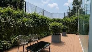 An outdoor deck with a wooden floor, two wicker chairs, a black bench, and potted plants. - Executive apartment Vistas del Bosque near Polanco (Mexico City)