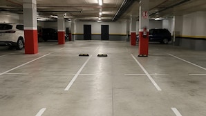 A parking garage with white and red pillars, numbered parking spaces, and a fire extinguisher on a red pillar. - Executive apartment Vistas del Bosque near Polanco (Mexico City)