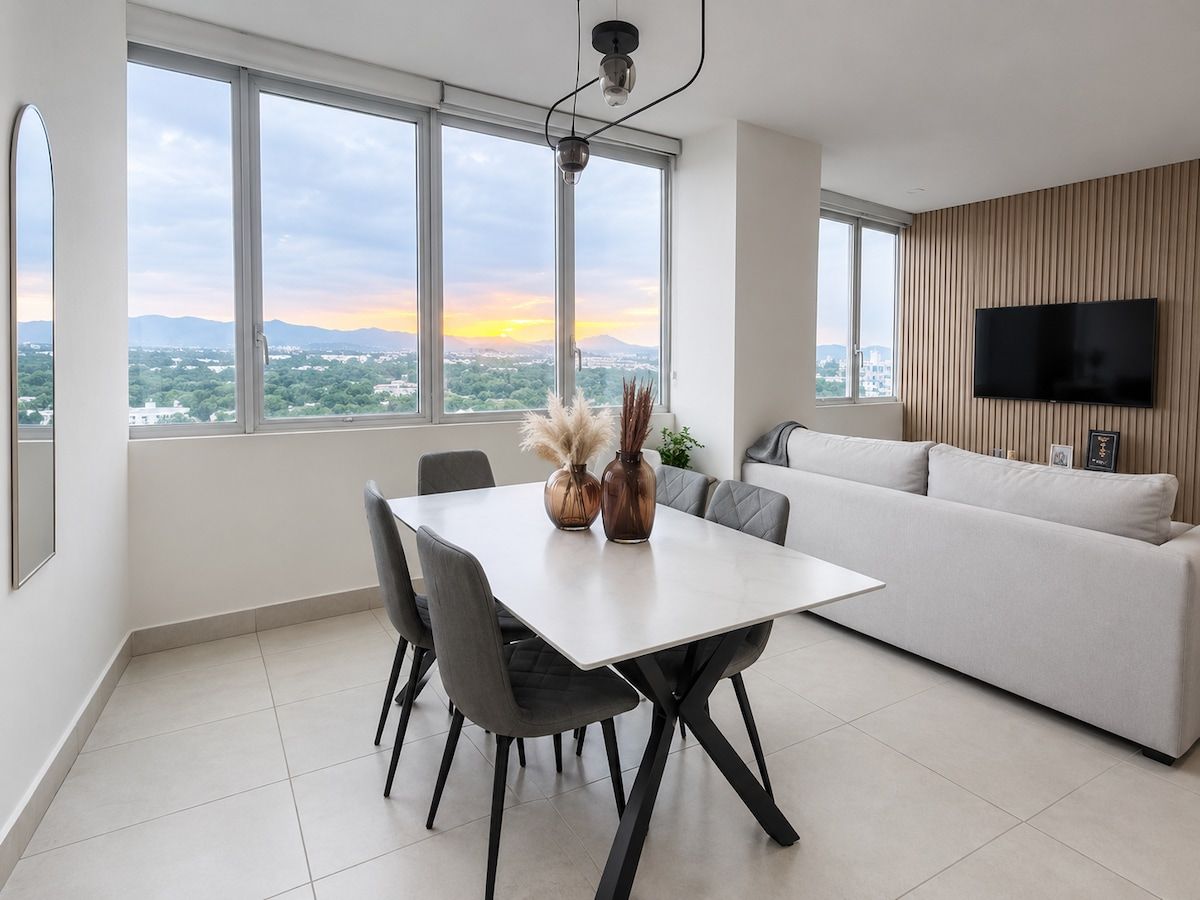 Un salon moderne comprenant un coin repas, de grandes fenêtres, un téléviseur à écran plat et une vue sur la ville.