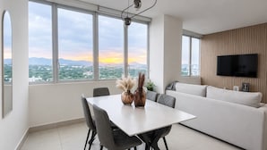 A modern living room with a dining area, large windows, a flat-screen TV, and a city view. - Executive apartment Vistas del Bosque near Polanco (Mexico City)